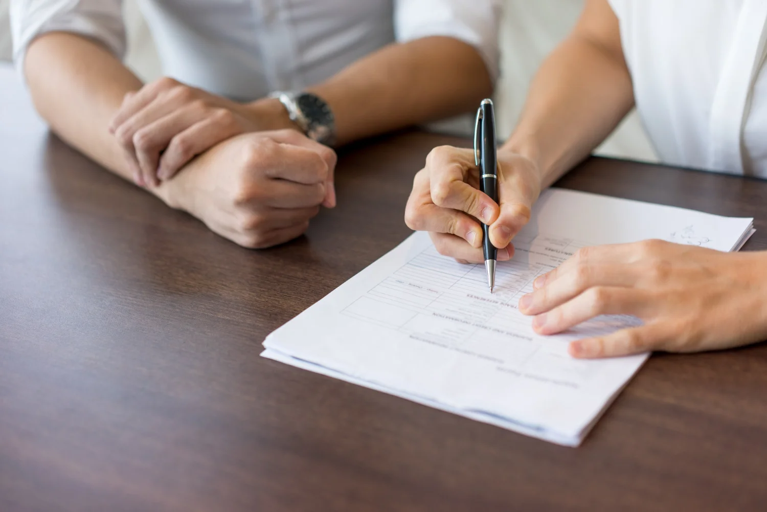 Dos personas firmando un documento encima de la mesa