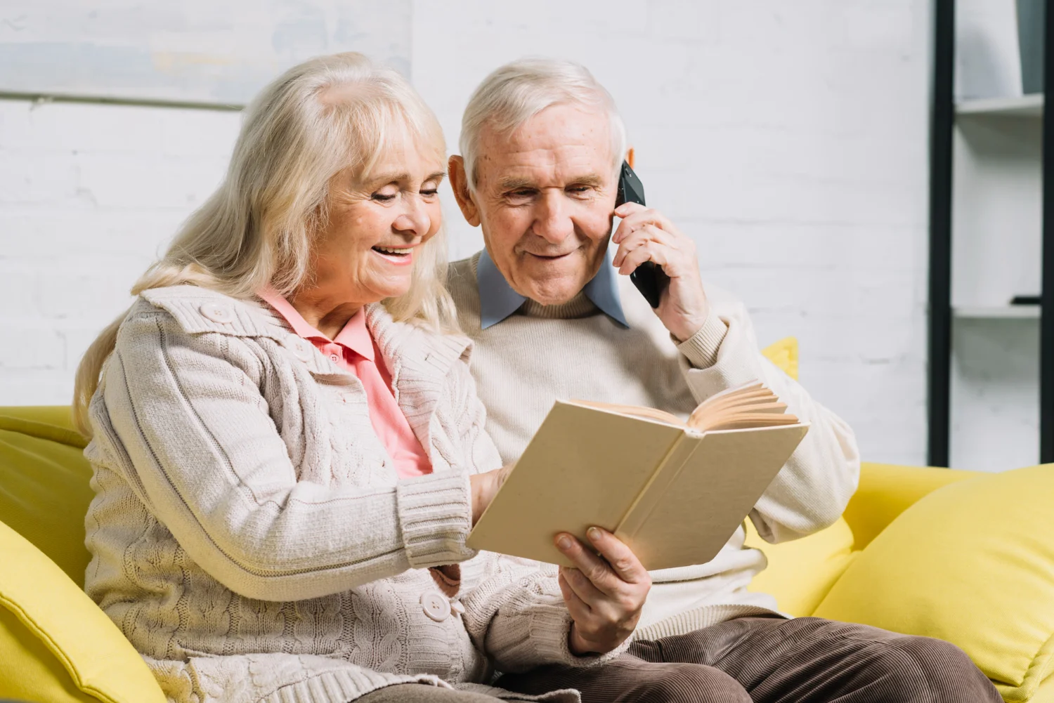 Dos personas mayores mirando una libreta y hablando por telefono